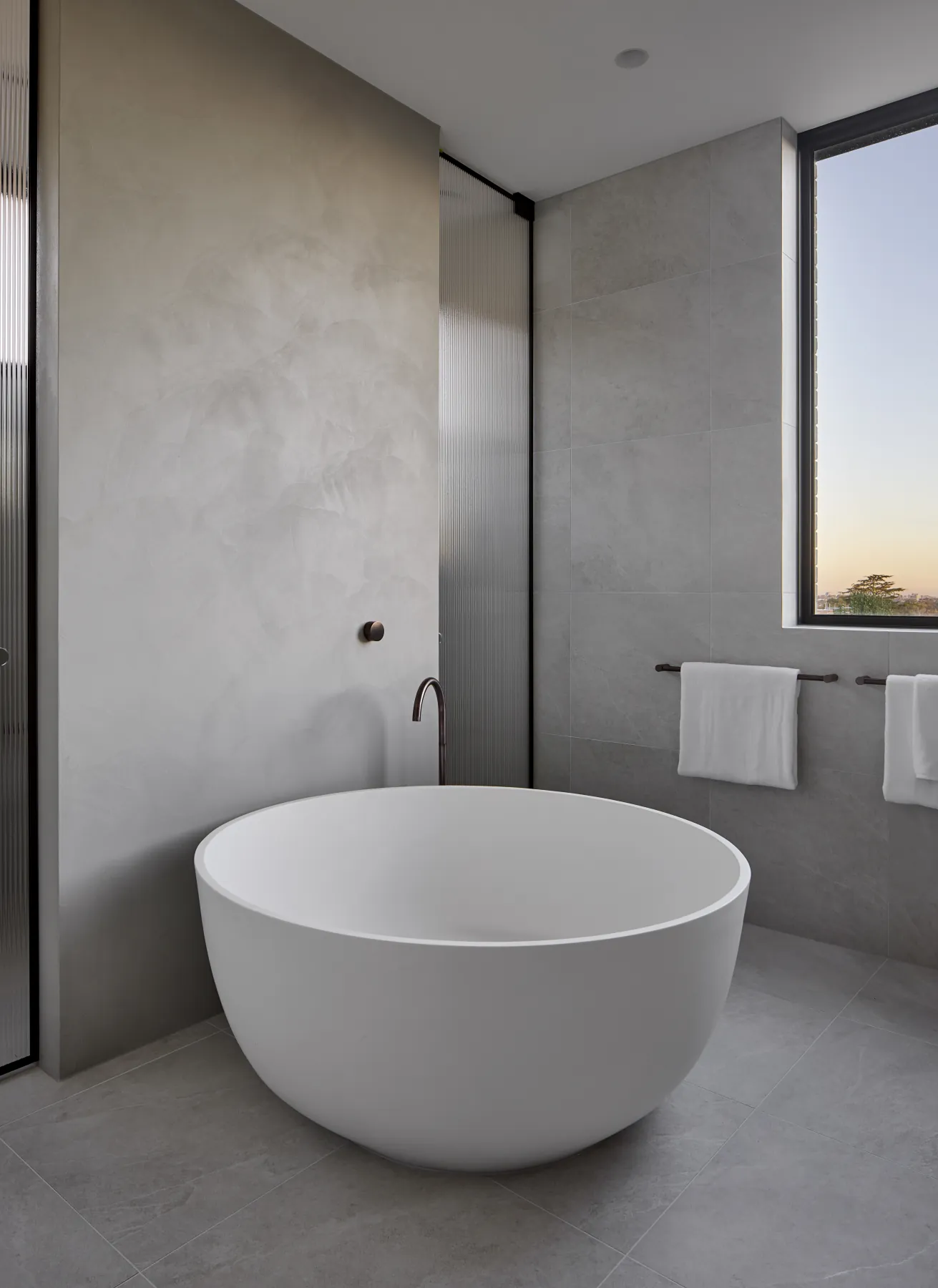 Ensuite renovation with a round freestanding bath, fluted glass screen and full-height window