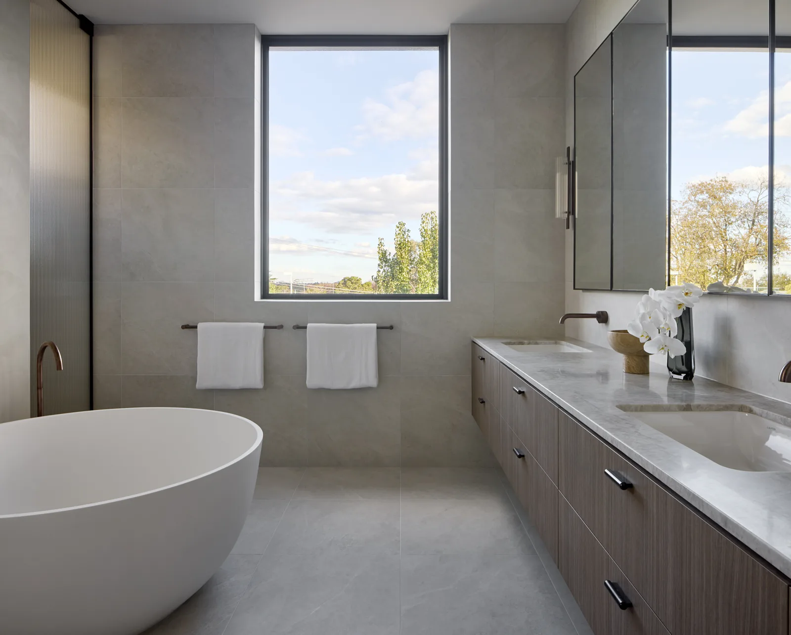 Completed bathroom with freestanding bath, stone tiling and timber vanity