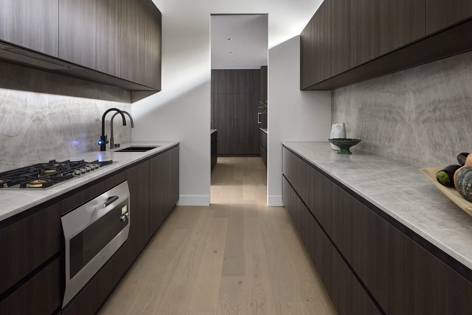 Completed galley kitchen with dark timber joinery and stone benchtops